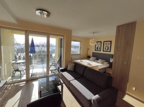 a living room with a couch and a bed and a table at Atrium Luksusowe Apartamenty in Sarbinowo