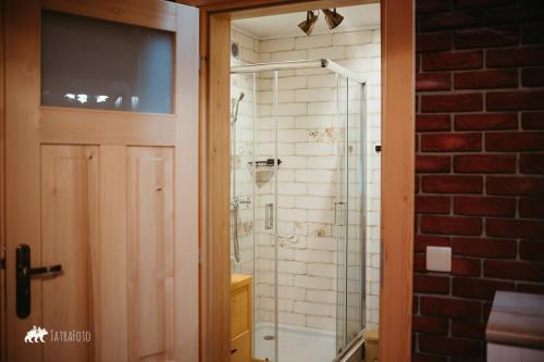 a bathroom with a shower and a glass door at Schronisko Stary Młyn in Zakopane