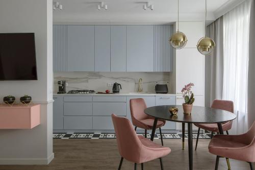 una cocina con mesa y sillas y una cocina con armarios blancos. en Flav Apartment en Cracovia