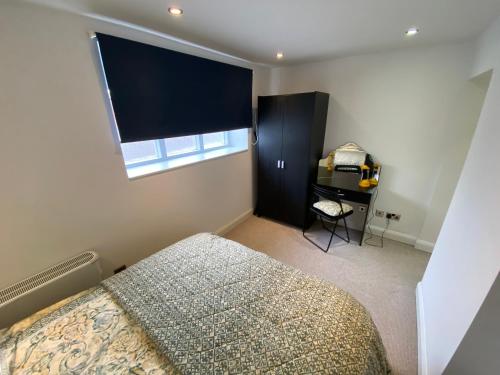 1 dormitorio con cama, ventana y escritorio en Buckingham House Apartment 2 en Macclesfield