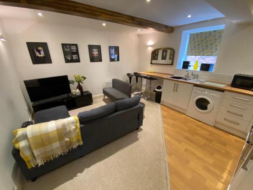 a living room with a couch and a washing machine at Buckingham House Apartment 2 in Macclesfield