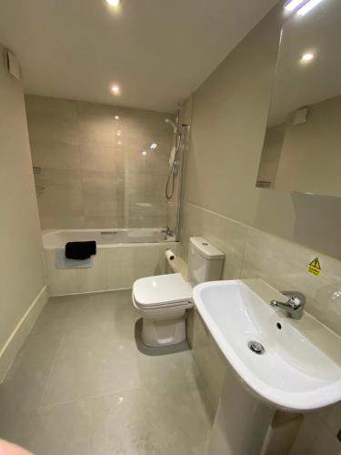 Baño blanco con lavabo y aseo en Buckingham House Apartment 2 en Macclesfield