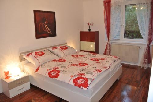 1 dormitorio con 1 cama con colcha de flores rojas en Apartment Paradies - U1 Station altes Landgut, en Viena