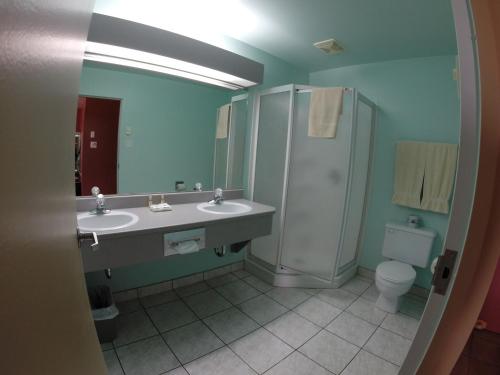 La salle de bains est pourvue de 2 lavabos, d'une douche et de toilettes. dans l'établissement Motel Le Pocatois, à La Pocatière