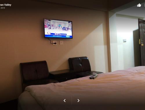 a hotel room with a bed and a flat screen tv at Arcadian Inn Hotel in Gilgit