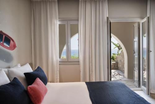 a bedroom with a bed and a large window at Poseidon of Paros Hotel & Spa in Chrissi Akti