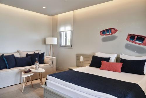 a bedroom with a bed and a couch at Poseidon of Paros Hotel & Spa in Chrissi Akti