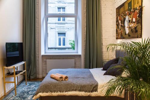 Schlafzimmer mit einem Bett und einem großen Fenster in der Unterkunft Sympatyczne studio z palmą areka / A nice studio with areka palm tree in Łódź