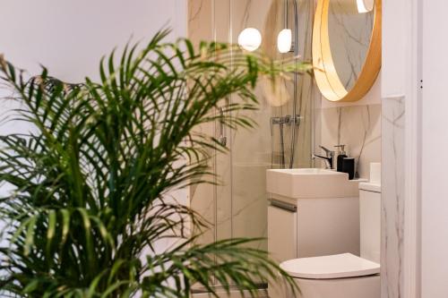 a bathroom with a sink and a toilet and a mirror at Sympatyczne studio z palmą areka / A nice studio with areka palm tree in Łódź