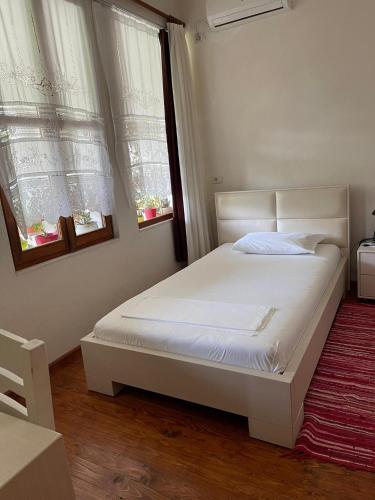 a white bed in a bedroom with two windows at Veranda B&B in Berat
