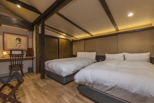 a bedroom with two beds and a desk with a chair at Shiki Homes KUMEI in Kyoto