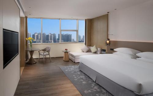 a hotel room with a bed and a couch at Golden Shining New Century Grand Hotel Beihai in Beihai
