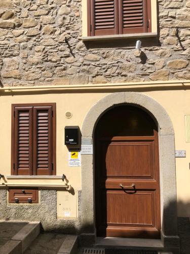 - un bâtiment avec une porte en bois et un mur en pierre dans l'établissement Basicò un balcone sul mare - Casa SALITA FOTI -Case vacanza Sicilia&Toscana-, à Basicò