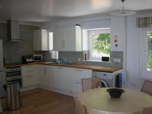 a kitchen with white cabinets and a table and a window at Beach View Apartment in Ventnor