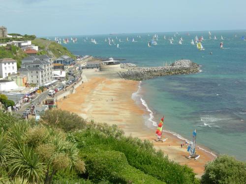 a beach with people and boats in the water at Beach View Apartment in Ventnor