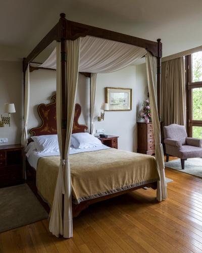 a bedroom with a canopy bed and a chair at Parador de Gijón in Gijón
