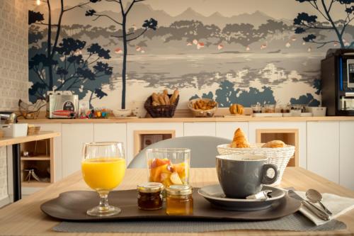 a table with a plate of food and a cup of orange juice at Hotel Mercedes in Hossegor