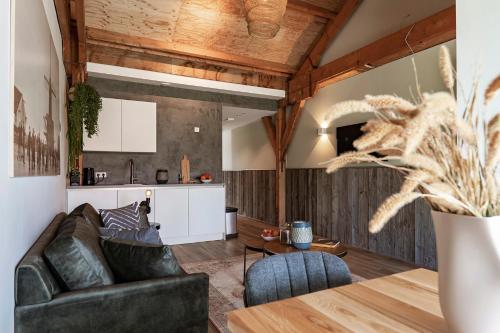ein Wohnzimmer mit einem Sofa und einem Tisch in der Unterkunft Erfgoedpark De Hoop Appartementen in Uitgeest