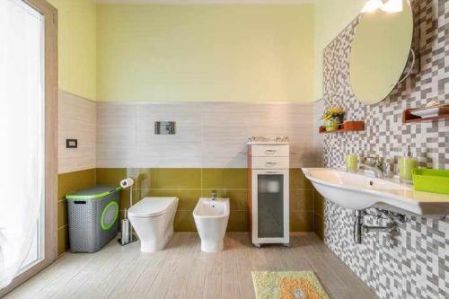 Un baño con lavabo, inodoro y espejo. en Larcobaleno di Chia, en Domus de Maria