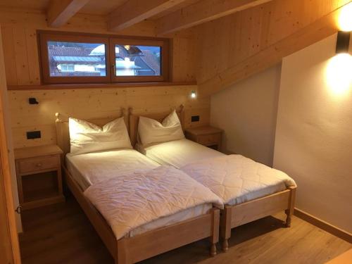 Ce lit se trouve dans une petite chambre dotée d'une fenêtre. dans l'établissement Appartamenti Cèsa Sorèie Dolomiti, à Canazei