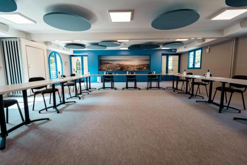 a room with tables and chairs and a painting on the wall at Hotel Mercedes in Hossegor