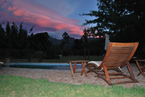 a wooden chair and a table next to a pool at Orange-Ville Lodge & Guesthouse in Stellenbosch