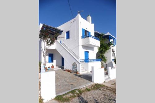 uma casa branca com janelas azuis e escadas em 3 min from the beach-White&blue house in Apollon em Apollon