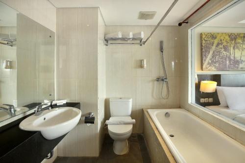 a bathroom with a sink and a toilet and a bath tub at Rofa Kuta Hotel - CHSE Certified in Legian