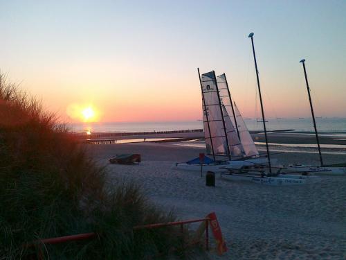 a sail boat on the beach at sunset at Atlantic Hotel Garni in Wangerooge
