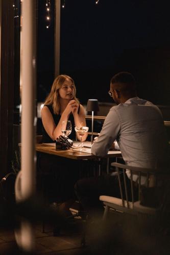 a man and a woman sitting at a table with wine glasses at Rossano Boutique Hotel & Ristorante in Ansbach