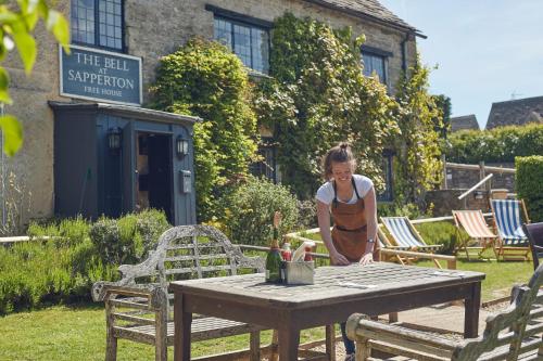 een vrouw die voor een tafel staat met een fles wijn bij The Bell at Sapperton in Cirencester
