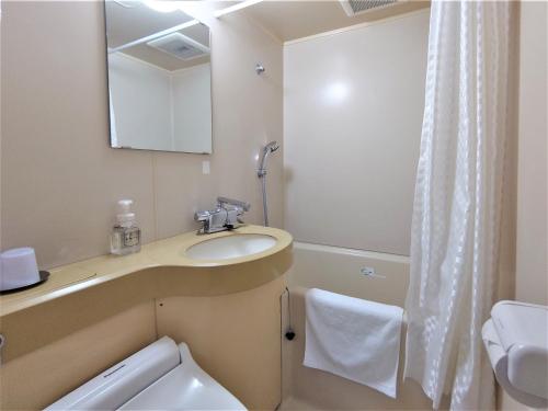 a bathroom with a sink and a toilet and a mirror at Hotel Area One Oita in Oita
