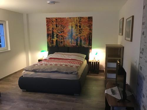 1 dormitorio con 1 cama con una pintura en la pared en Apartment Ferienwohnung Brandmatt - Weitblick - 54qm, en Sasbachwalden