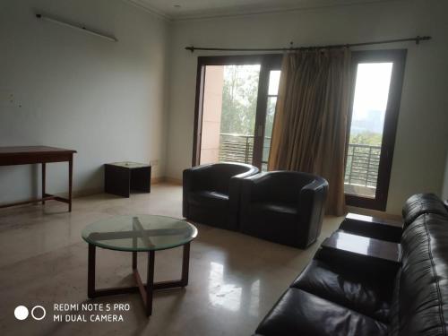 a living room with a leather couch and a glass table at Deluxe Suite in Manor Inn Suites B-54, Sector-92 in Noida