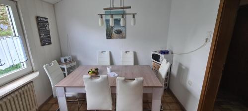 a kitchen with a wooden table and white chairs at Lichtblick in Wangerland