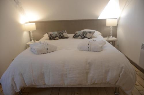 a bedroom with a white bed with two lamps at Le Murmure des Fées in Issigeac