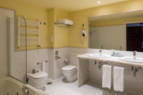 a bathroom with two sinks and a toilet and a shower at Parador de Tortosa in Tortosa
