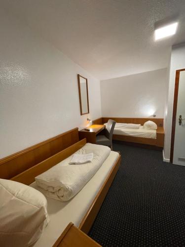 エッセンにあるブルネン ホテルのベッド2台とデスクが備わるホテルルームです。