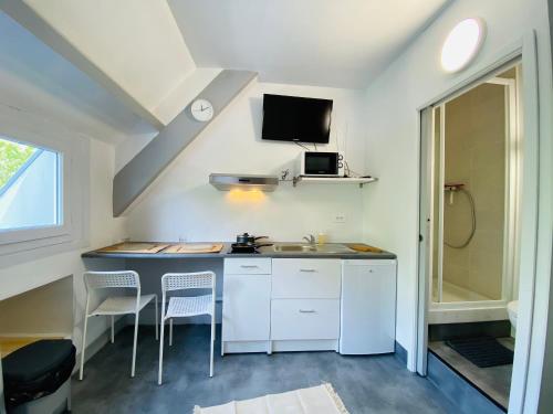 eine Küche mit einer Spüle und einer Theke mit Stühlen in der Unterkunft STUDIO proche commodité et gare . Centre ville in Caen