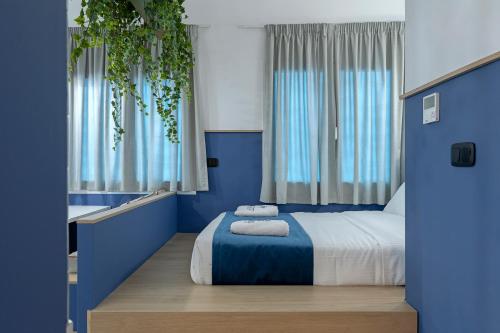 a bedroom with a bed with blue walls and windows at Acro Urban Suites in Athens