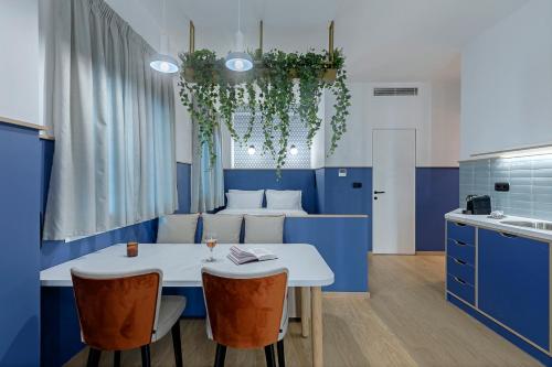 Acro Urban Suites في أثينا: مطبخ مع دواليب زرقاء وطاولة وكراسي بيضاء