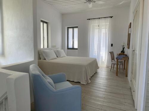 a white bedroom with a bed and a chair at Raphael Skiathos Living-Olga in Skiathos Town