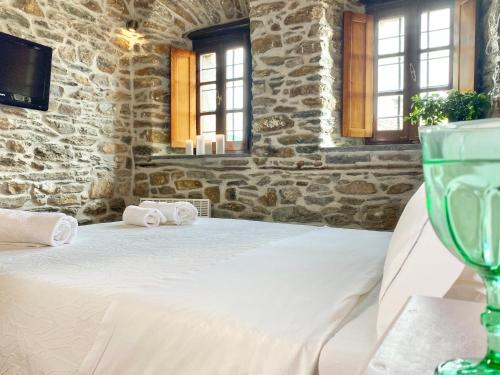 a table with a white bed in a stone room at Archontika Karamarlis in Makrinítsa