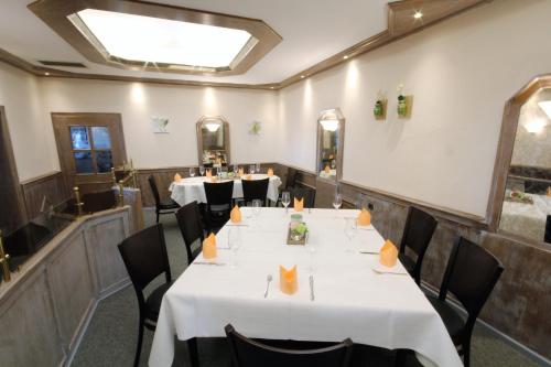 a dining room with white tables and black chairs at Hotel Pfennigskrug in Herford