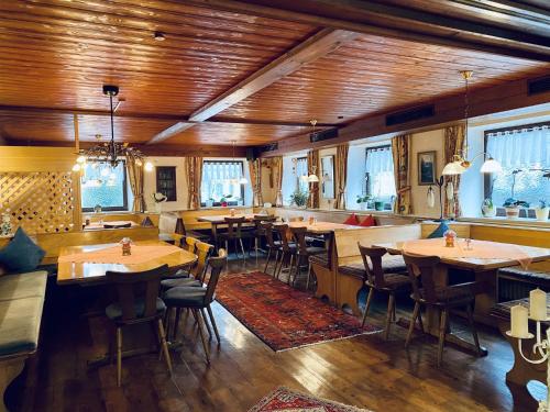 a restaurant with wooden ceilings and tables and chairs at Pension Hirsch in Seeg