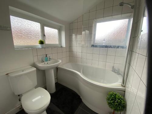 a bathroom with a toilet and a tub and a sink at Edinburgh Place in Kettering