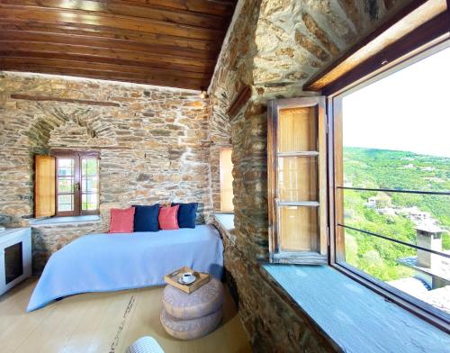 um quarto com uma cama e uma grande janela em Archontika Karamarlis em Makrinitsa