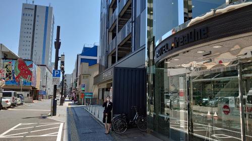 a person standing on a city street next to a store at Hotel Area One Oita in Oita