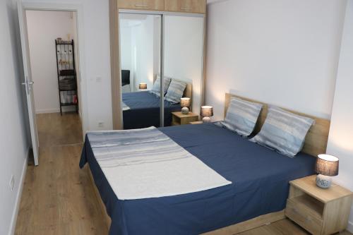 a bedroom with a blue bed and a mirror at CityApart GranVia Marina - Cazare în Constanța, lângă stațiunea Mamaia in Constanţa