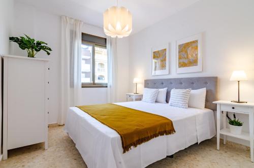 een witte slaapkamer met een groot bed met een gele deken bij Del Parque Flats Candelaria Rincon in Rincón de la Victoria